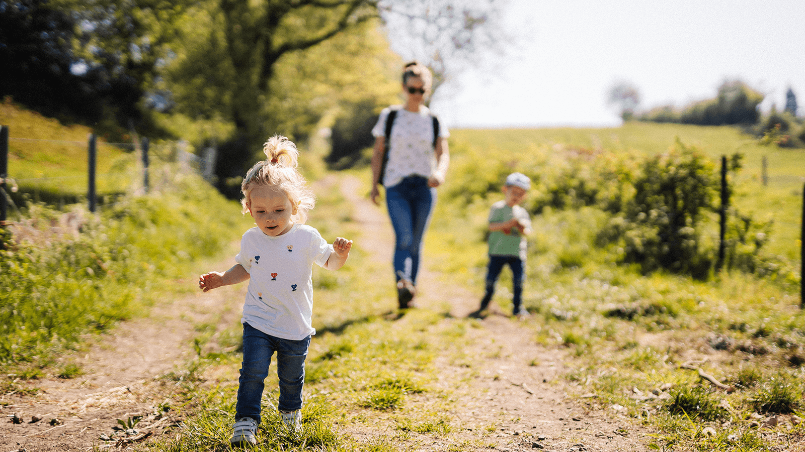 Bewegung im Alltag mit Kindern: Familie auf Frühlingsspaziergang in ländlicher Umgebung – gesund bleiben mit spielerischer Aktivität
