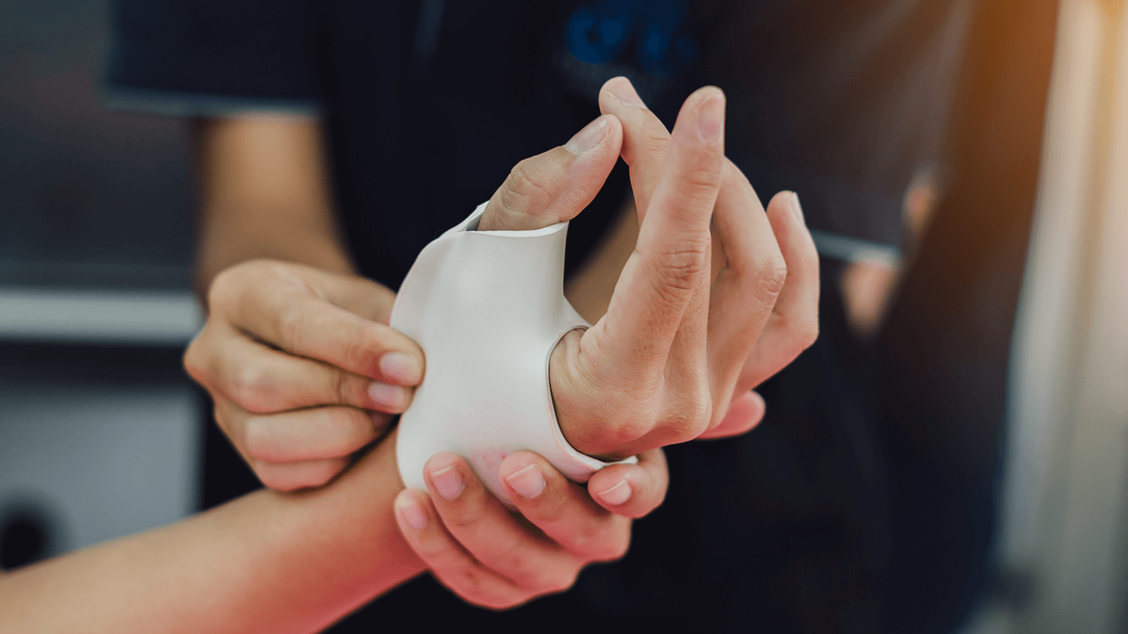 Therapeut passt eine individuell angefertigte Schiene an den Daumen einer Hand an – Einsatz in der Handtherapie zur Stabilisierung, Schmerzlinderung oder funktionellen Unterstützung nach Verletzung oder Operation.